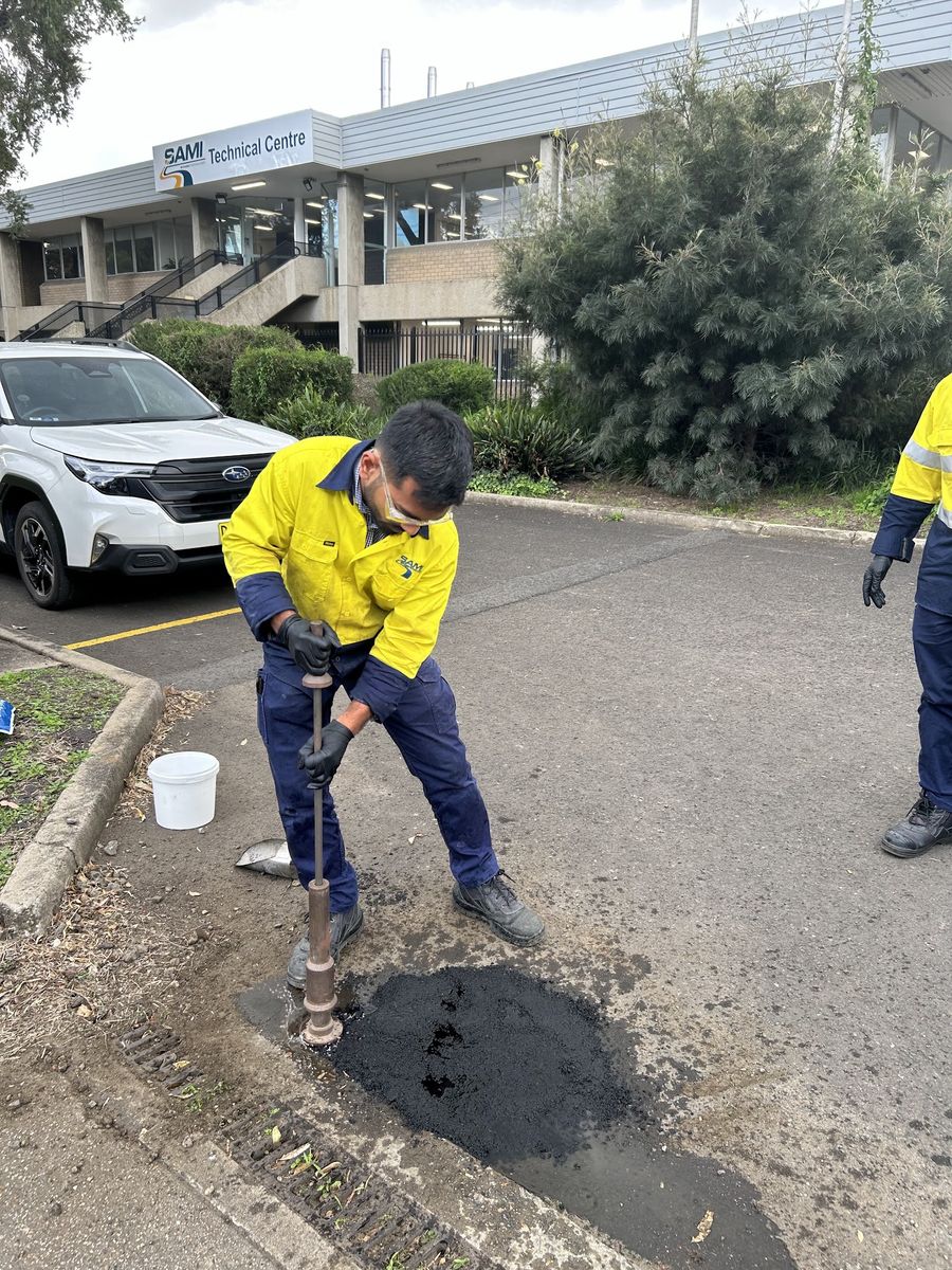 Worker pouring Aqua Patch into a pothole